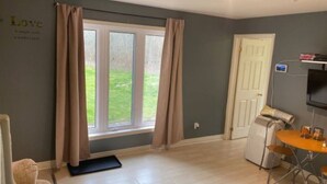 A room with a large window, a door, a TV mounted on the wall, and a small table with chairs. - The Little Jurassic Lake House.<br>keep in mind sometime Satellite TV Doesn’t work. (Carrying Place)