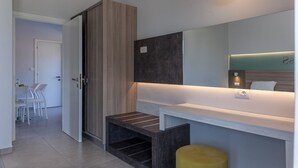 A modern bathroom with a large mirror, a wooden wardrobe, and a small bench.