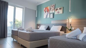 A hotel room with two beds, a large window, and artwork on the wall.