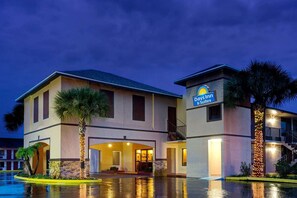 A hotel with a pool, a sign for Days Inn & Suites, and a two-story building with a balcony. - Days Inn at Oak Plantation (Kissimmee)
