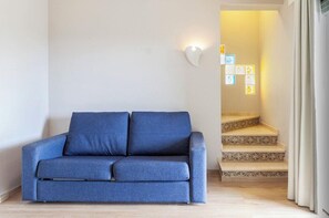 A blue sofa in a room with a staircase leading to a lit area.