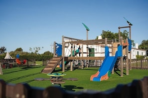 A playground with a slide, climbing structures, and a small table.