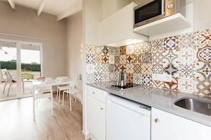 A modern kitchen with patterned tiles, a built-in oven, and a dining area with white furniture.