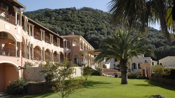 A hotel with a courtyard, palm trees, and a mountainous backdrop. - Philoxenia Hotel (Corfu)