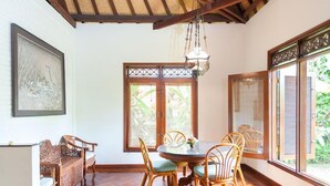 A dining area with a round table, wooden chairs, and a hanging light fixture. - Villa Chempaka (Ubud)