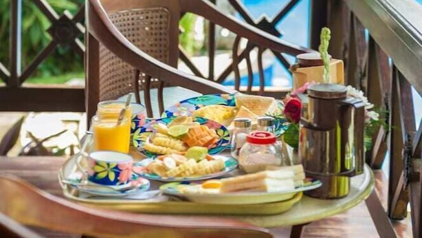 A breakfast tray on a wooden table with a tropical garden view. - Villa Chempaka (Ubud)
