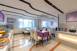 A modern dining area with a buffet on the left, a reception desk on the right, and a large window providing natural light.