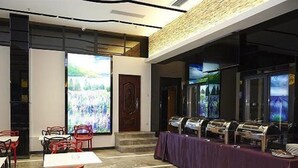 A dining area with tables and chairs, a buffet line, and a large screen displaying a landscape. - Lavande Hotel (Zhanjiang)