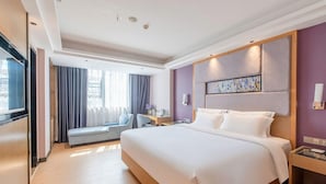 A hotel room with a large bed, a desk, a chair, a window with curtains, and a painting on the wall. - Lavande Hotel (Zhanjiang)