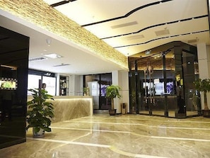 A hotel lobby with a reception desk, a seating area, and a glass elevator. - Lavande Hotel (Zhanjiang)