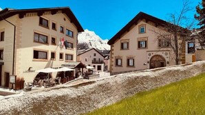 A hotel with multiple buildings, a mountain in the background, and a grassy slope. - Albana (Silvaplana)