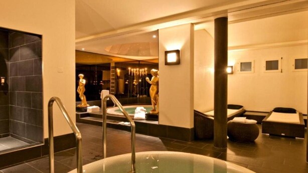 A modern spa area with a hot tub, seating, and a large mirror reflecting the space. - Albana (Silvaplana)
