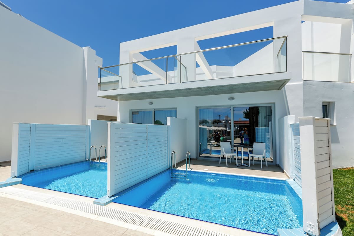 Un edificio moderno con piscina, patio coperto e porta in vetro che dà su una zona relax all'aperto.