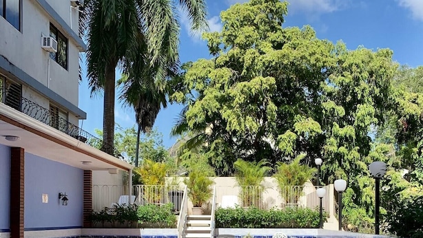 A swimming pool with a tiled deck, white outdoor furniture, and a staircase leading to a balcony. - Eurohotel Panama (Panama City)