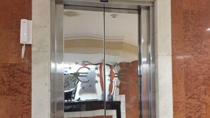 A double elevator door with a digital display above it, a telephone, and a wall with a marble pattern. - Eurohotel Panama (Panama City)