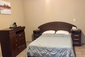 Ein Schlafzimmer mit einem Bett, zwei Nachttischen, einer Kommode und einem Bild an der Wand.