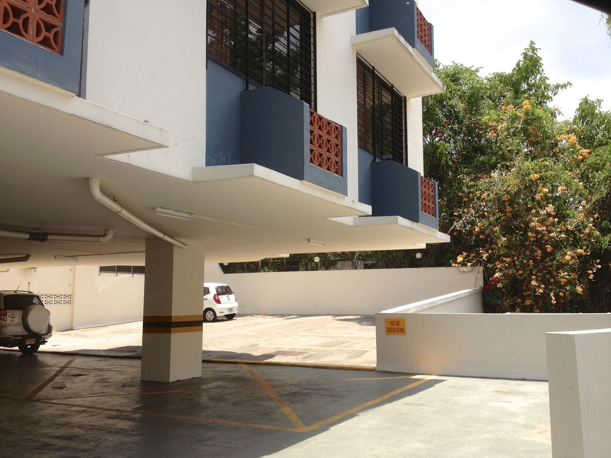 Un edificio de varios pisos con un estacionamiento al frente.