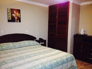 Une chambre à coucher avec un lit, une armoire, une table de chevet et un tableau au mur.