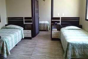 Quarto com duas camas, cada uma com cabeceira, mesas de cabeceira e uma pequena gaveta.