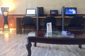 Un espace d’accueil comprenant un bureau, des ordinateurs, des chaises et une lampe.