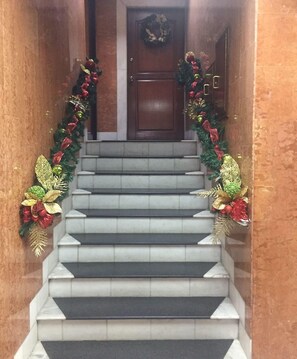 Un escalier décoré d’une guirlande de Noël et d’une couronne accrochée à la porte.