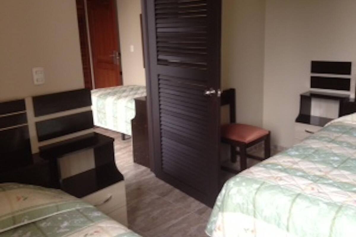 Ein Schlafzimmer mit einem Bett, einem Sessel, einem Schreibtisch und einem Kleiderschrank.