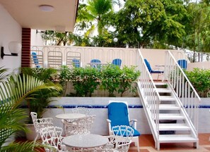 Una terraza con mobiliario exterior, una escalera y vistas al entorno verde.