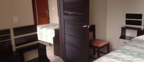 Un dormitorio con una cama, una silla, un escritorio y un armario.