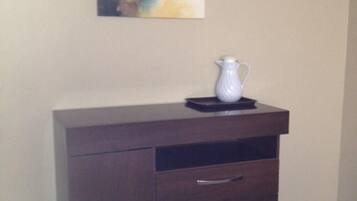A dark wooden cabinet with drawers and a pitcher on top.