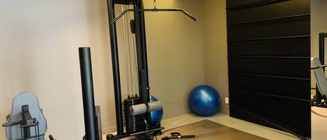 A home gym with a pull-up bar, weight bench, and exercise ball.