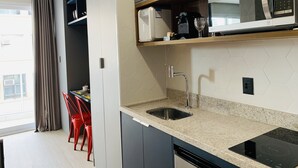 Eine moderne Küche mit eingebauter Mikrowelle, einem Edelstahl-Spülbecken und einer schwarzen Induktionskochplatte.