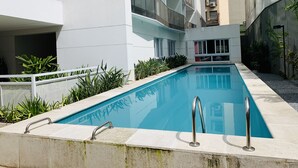 Ein Schwimmbecken mit modernem Design, umgeben von einem Gebäude mit weißen Balkonen.