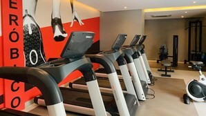 Ein Fitnessstudio mit mehreren Laufbändern, einer Wand mit einer großen Werbung und einer Decke mit Einbaustrahlern.