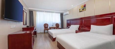 Ein Hotelzimmer mit zwei Betten, einem Fernseher, einem Schreibtisch und einem Sessel.