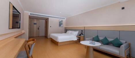 A hotel room with a bed, a sofa, a dining table, and a chair.