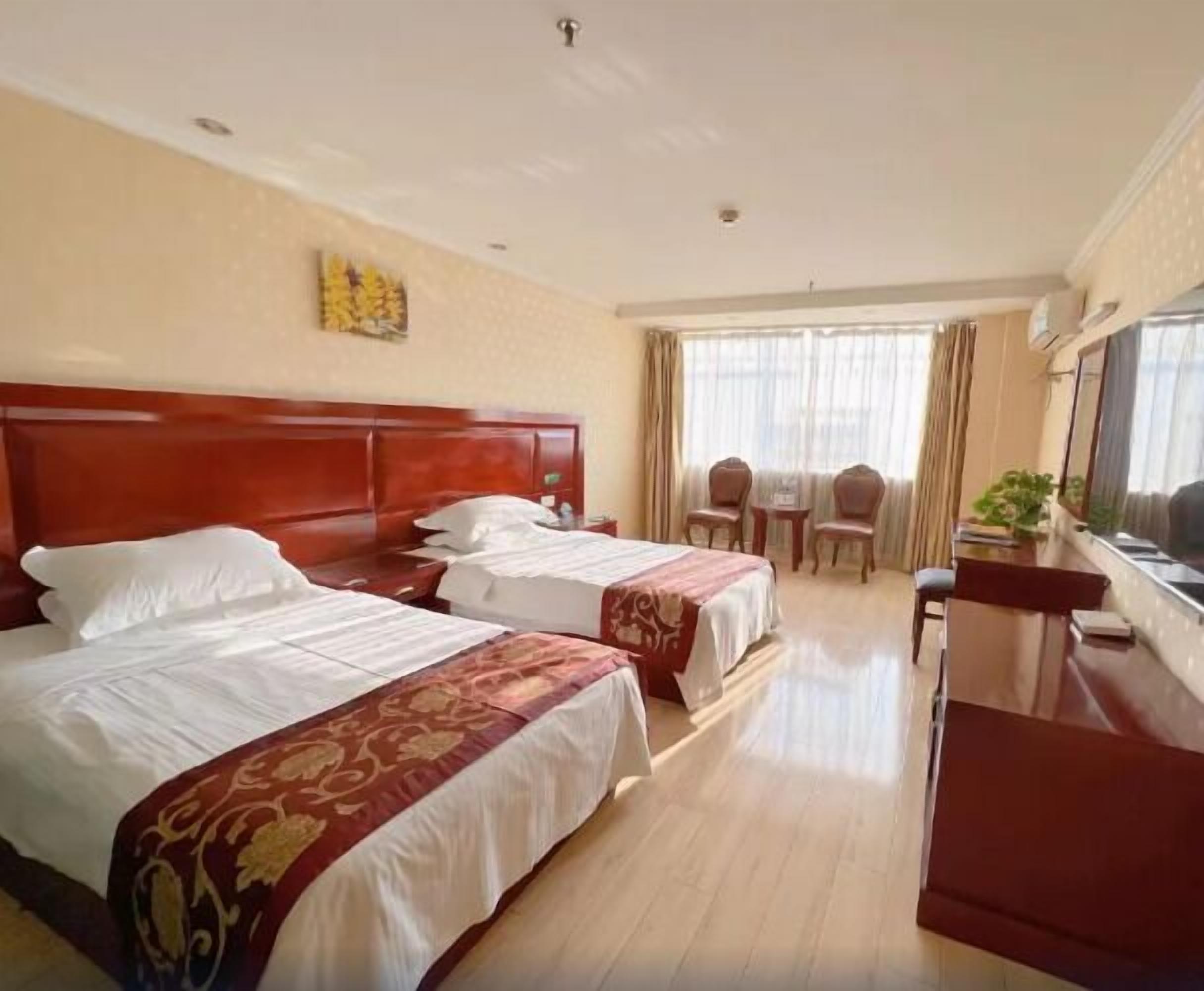 Une chambre d’hôtel avec deux lits, un bureau, des chaises et une grande fenêtre.