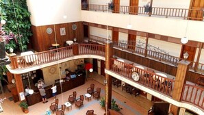 A multi-level hotel lobby with a central atrium, wooden railings, and multiple seating areas. - Ozcan Hotel (Marmaris)