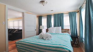 Een hotelkamer met een bed, een stoel, een tafel en een bank in de aangrenzende kamer.