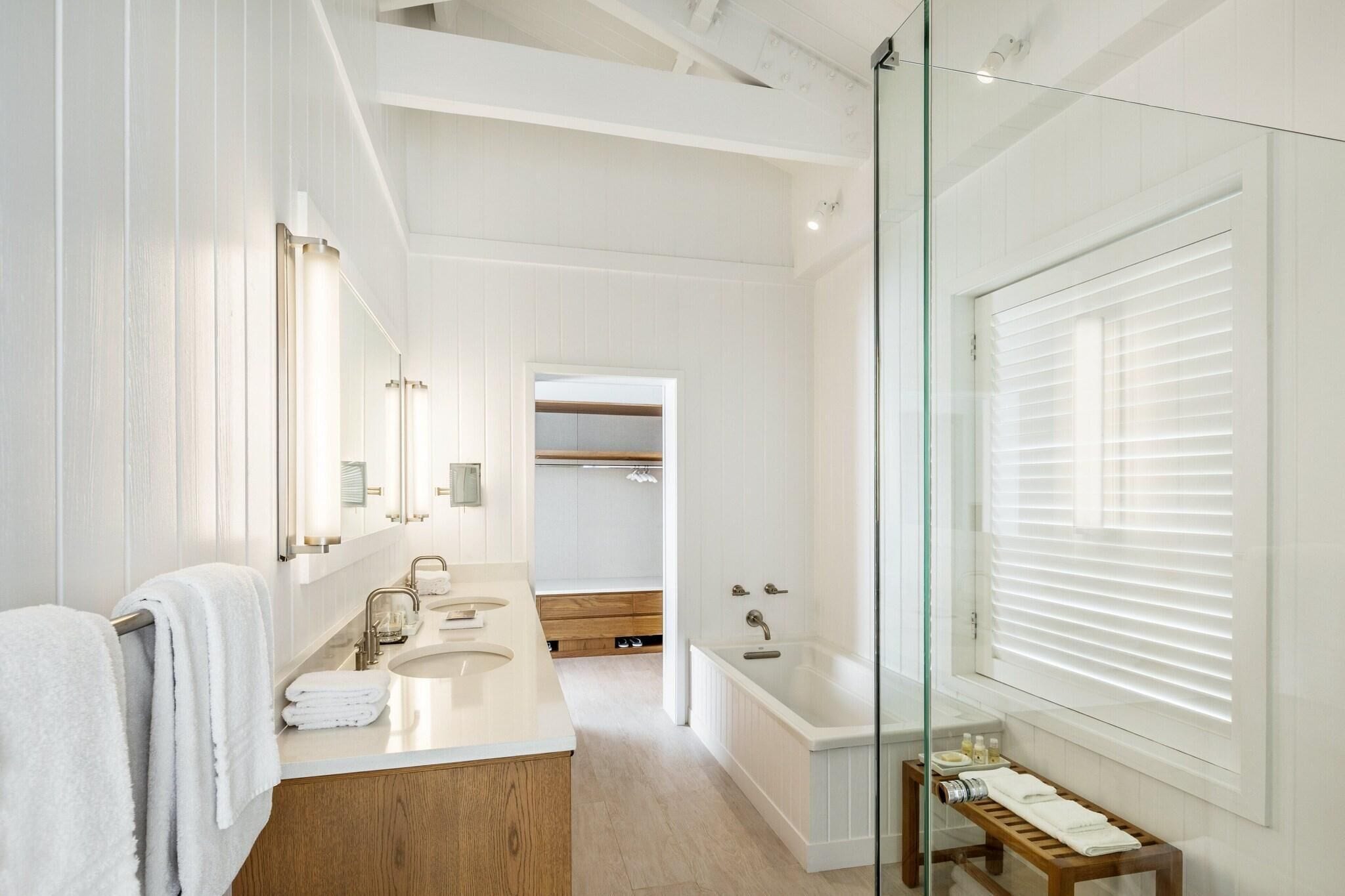 A modern bathroom with a glass shower enclosure, a large mirror, and a wooden vanity.