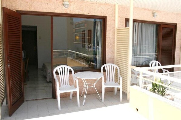An outdoor balcony with a glass door leading to a room, white plastic chairs, and a small round table. - La Nina (Sant Llorenc des Cardassar)