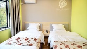 Une chambre d’hôtel avec deux lits, une fenêtre avec des rideaux, un appareil de climatisation et un mur orné d’un logo et d’un texte.
