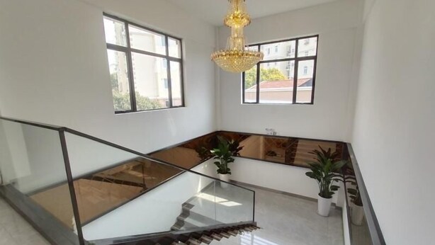 Un intérieur moderne avec un escalier en verre, de grandes fenêtres et un lustre.