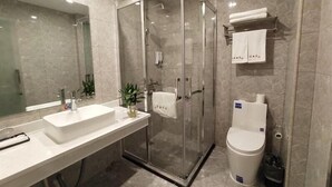 Une salle de bain moderne avec une douche à parois de verre, un lavabo blanc et des toilettes.