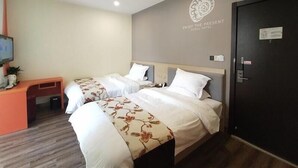 Une chambre d’hôtel avec deux lits, un bureau et une télévision.