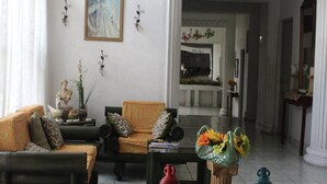 A living room with two sofas, a coffee table, and decorative items. There is a statue on a side table and a painting on the wall. - Grecia Real Hotel (San Salvador)