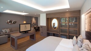 A modern hotel room with a bed, a desk, a sofa, and a TV.