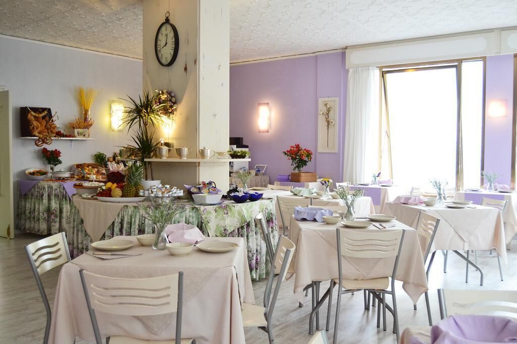 A dining area with multiple tables set for a meal, a clock on the wall, and various decorative items.