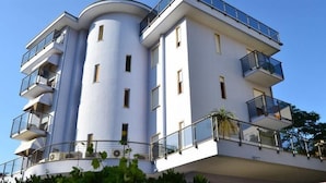 A modern multi-story building with balconies and a curved facade. - My Fair Hotel (Jesolo)