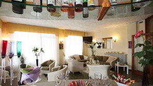 A well-lit living room with a glass-top coffee table, several chairs, a sofa, and a television. - My Fair Hotel (Jesolo)