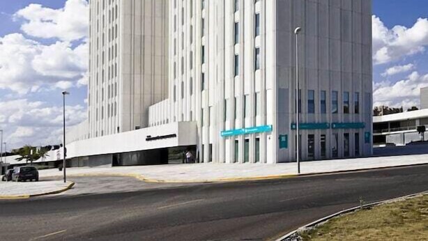 A modern high-rise building with a unique vertical design, featuring a series of vertical lines and a flat roof. - YIT Via Sevilla Mairena (Mairena del Aljarafe)